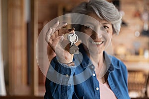 Happy old middle aged sincere woman holding keys in hands.