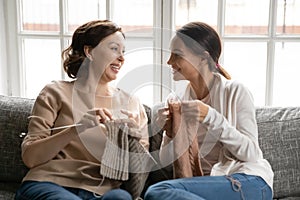 Happy old mom and adult daughter knit together