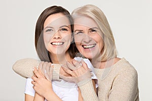 Happy old mother embracing young daughter isolated on background