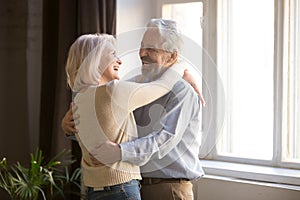 Happy old retired romantic couple dancing laughing in living room