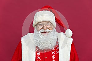 Happy old Santa Claus looking at camera standing on red background, headshot. photo