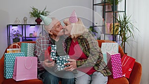 Happy old senior family grandparents man woman celebrating birthday anniversary on couch at home
