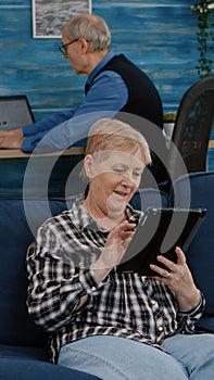 Happy old senior grandmother holding digital tablet browsing informations