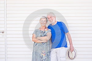 Happy old senior people caucasian couple standing and posing smiling with wooden white wall background - bright image with silver