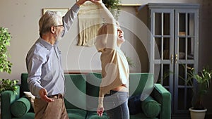 Happy old senior romantic couple dancing in modern living room