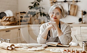 Happy old woman Granny cooks in kitchen kneads dough, bakes cookies