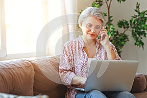 Happy old woman senior working at computer laptop at home