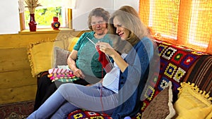 Happy old woman spend time knitting with pregnant granddaughter