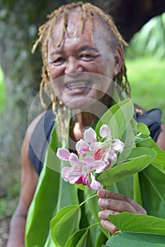 Happy Olde aged Pacific Islander man gives an exotic flower on e