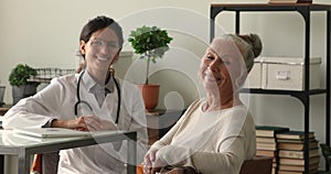 Happy older 60s woman posing with smiling young doctor.