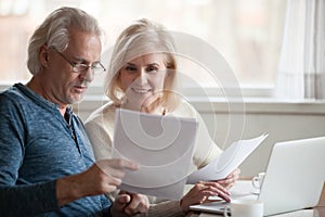 Happy older aged couple holding reading good news in document