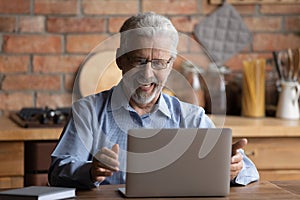 Happy older businessman excited of reading email with good news.