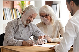 Happy older couple clients sign insurance contract meeting agent