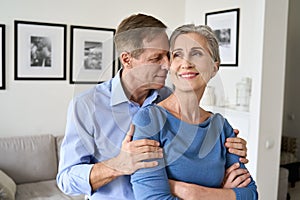 Happy older couple hugging, bonding, looking away dreaming of good future.