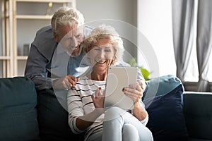 Happy older couple using computer tablet together at home photo