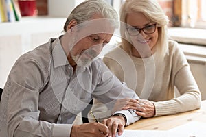 Happy older family couple husband and wife sign legal paper