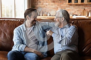 Happy older father and adult son relax at home