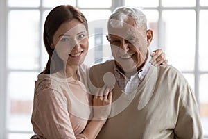 Happy older father and grown daughter hugging looking at camera