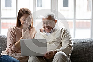 Happy older father and grownup daughter looking at laptop screen