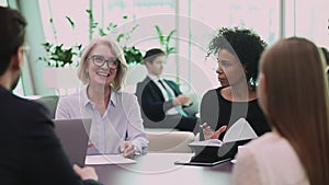 Happy older female leader discussing project details with employees.