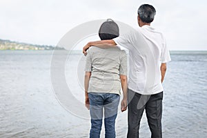 Happy older married man and woman standing on the beach together
