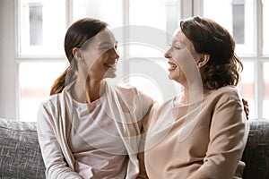 Happy older mom and adult daughter hug relaxing