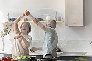 Happy older retired man dancing with elderly wife.