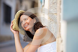 Happy older woman laughing with hat outside