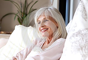 Happy older woman sitting on couch relaxed and smiling