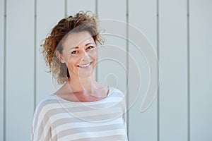 Happy older woman smiling against white wall