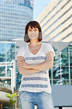 Happy older woman standing in city with arms crossed