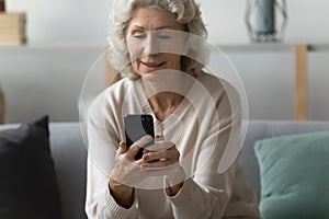 Happy older woman using smartphone for video call from home