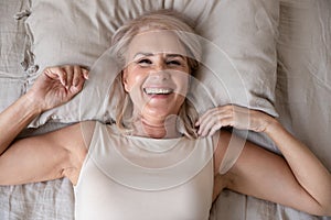 Happy older woman wake up in bed, top view