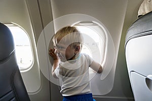Happy one year old baby boy next to airplain`s window