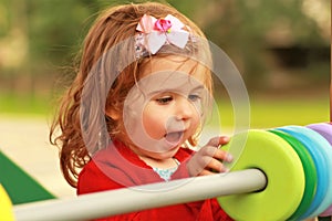 Happy one year old girl playing with wooden colorful circles