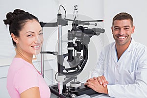 Happy optician and female patient with slit lamp