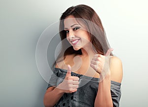 Happy optimistic brunette woman showing thumb up sign on blue ba