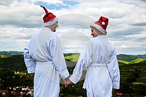 Happy Ñouple in a white coat and Santa Helper Hats on the mountain