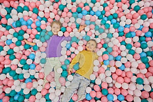 Happy overjoyed children lying in huge dry pool with plastic balls photo