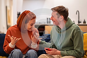 Happy overjoyed couple man woman reading good news in smartphone sitting on couch at home.