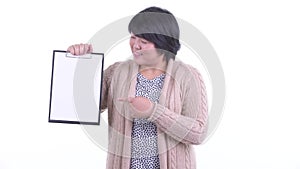 Happy overweight Asian woman showing clipboard and giving thumbs up ready for winter