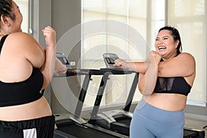 Happy Overweight Asian woman stretching before some main exercises in gym. Weight loss workout, healthy lifestyle concept