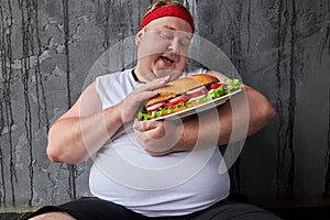 Happy overweight guy stroking a sandwich, treats food with care