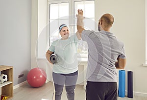 Happy, overweight woman and her personal sports trainer give each other high five