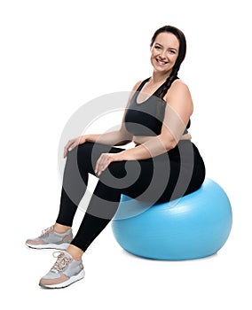 Happy overweight woman sitting on fitness ball against background