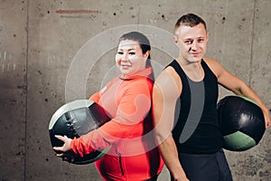 Happy overweight woman and slim man holding exercise balls