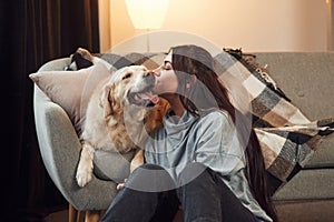 Happy owner of beautiful animal. Woman is with golden retriever dog at home