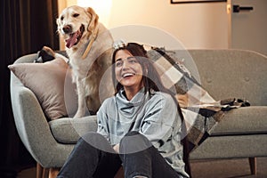 Happy owner of beautiful animal. Woman is with golden retriever dog at home