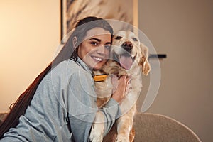 Happy owner of beautiful animal. Woman is with golden retriever dog at home