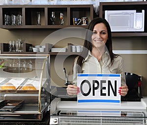 Happy owner of a cafe showing open sign